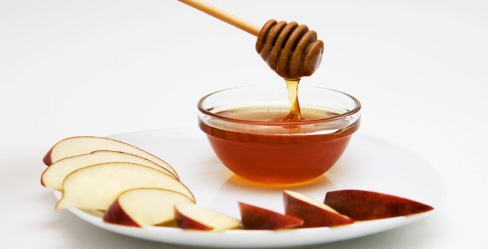 Apple slices and bowl of honey on a plate